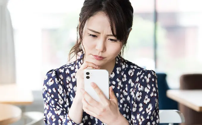 スマホが壊れて困っている女性の画像